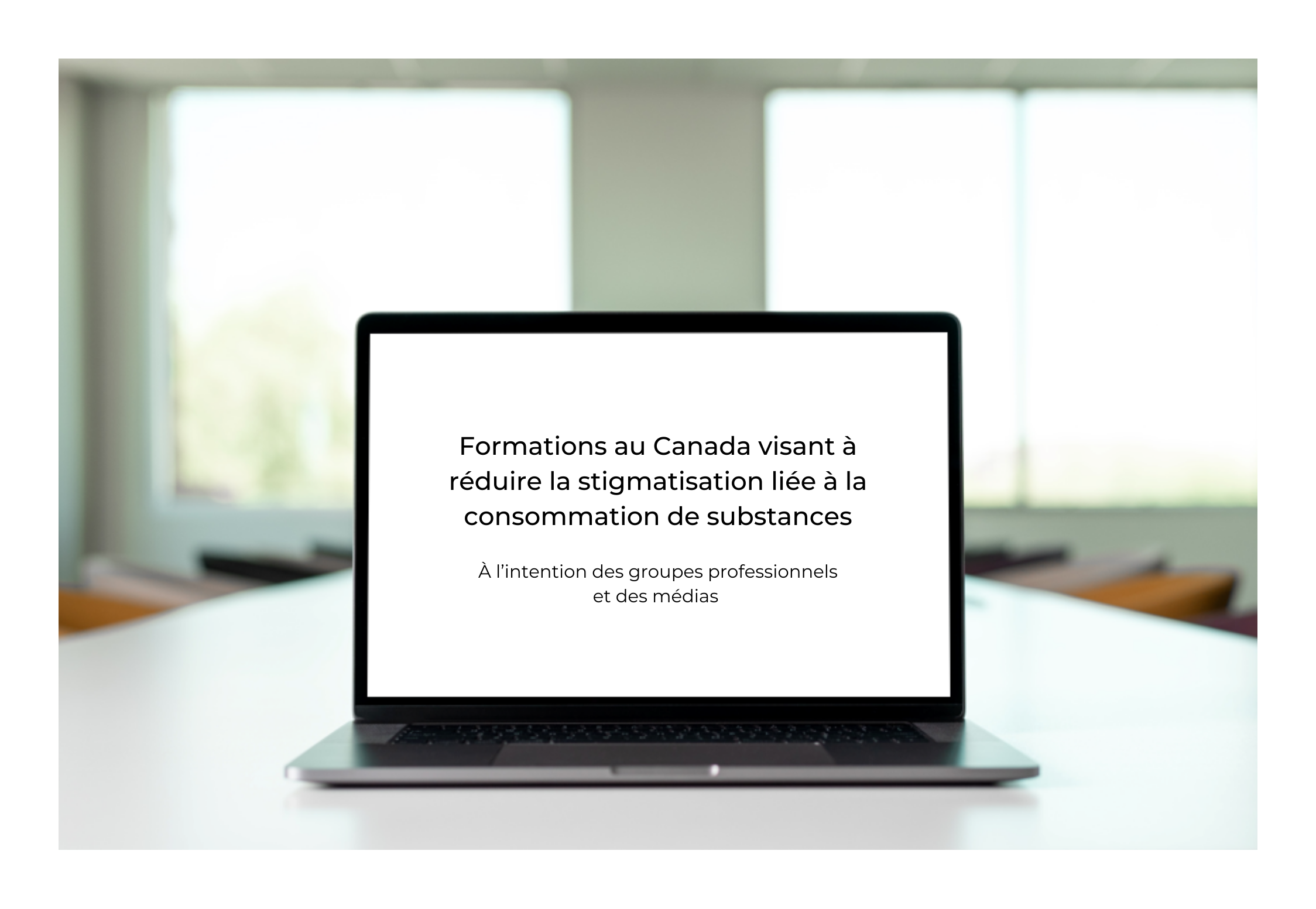Ordinateur portable ouvert sur un table de conférence. Sur l'écran est écrit: Formations au Canada visant à réduire la stigmatisation liée à la consommation de substances en noir sur un fond blanc. 